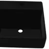 A close-up, top-down view of a black ceramic washbasin with a hole for a faucet and overflow. Produktbild-Vorschau