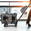 A person is pulling a pet carrier on wheels through an airport terminal, with an airplane visible through the windows. Náhled obrázku produktu