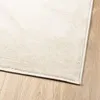 Close-up view of a beige rug on a wooden floor. Produktbild-Vorschau