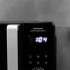A close-up view of the digital display and control panel of a black microwave oven. Produktbild-Vorschau