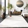 A modern living room with a large rug, sofa, and decorative items.