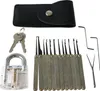 A collection of lock picking tools, a transparent practice lock, and keys are arranged on a white background. Produktbild-Vorschau