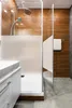 A modern bathroom with a shower, vanity, and wooden accent walls. Podgląd zdjęcia produktu