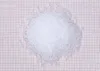 A pile of small white plastic pellets on a grid background. Podgląd zdjęcia produktu