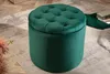 A dark green velvet ottoman sits on a rug in a room. Produktbild-Vorschau