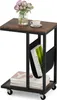 A side view of a C-shaped side table with a wooden top and black metal frame, featuring a magazine holder and books on the lower shelf. Voir les images du produit