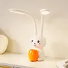 A white rabbit-shaped LED desk lamp with an orange cup holder sits on a white shelf. Produktbild-Vorschau