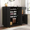 A black shoe cabinet with doors open, displaying shoes and boots on shelves, with a drawer partially open on top. Podgląd zdjęcia produktu