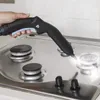 A hand is using a steam cleaner to clean a gas stove. Podgląd zdjęcia produktu