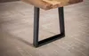 A close-up view of a wooden bench leg and part of the tabletop, resting on a textured rug. Náhled obrázku produktu