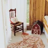 A child's bedroom with a chair, a rug, and a toy barn. Voir les images du produit