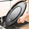 A person is rinsing a black electric hot pot grill under a faucet in a kitchen sink. Voir les images du produit
