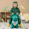 A young child dressed in a green dinosaur costume is happily riding a green inflatable dinosaur toy in a child's room. Podgląd zdjęcia produktu