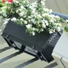 A black rectangular planter box with white flowers and some pink flowers, attached to a railing. Voir les images du produit