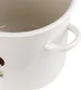 A close-up view of the side of a cream-colored enamel pot with two handles. A small illustration of a mushroom and grass is visible on the left side of the pot. Podgląd zdjęcia produktu