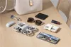 A collection of personal items including a drone, sunglasses, lipstick, wallet, and smartphone are arranged on a wooden surface. Anteprima dell’immagine prodotto