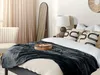 A bedroom scene with a bed, blanket, pillows, chair, and mirror. Podgląd zdjęcia produktu