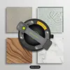 A vacuum lifter is shown centrally, surrounded by four different material samples: stone, glass, wood, and marble. Produktbild-Vorschau