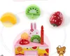A collection of toy food items, including fruits and a cake, arranged around a pink cake base. Podgląd zdjęcia produktu