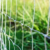 A close-up of a wire fence with a blurred green background of grass. Produktbild-Vorschau
