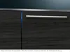 A close-up view of a dark wood-grained cabinet with a silver handle and a thin blue light strip. Náhled obrázku produktu