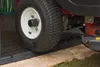 A close-up view of a lawnmower tire on a black ramp, with part of the lawnmower visible. Náhľad obrázku produktu