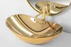 A close-up shot of a gold oval vessel sink with a gold faucet, reflected in a circular mirror. Náhled obrázku produktu