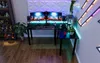A gaming setup with dual monitors, a desk, and a display cabinet filled with collectibles. Produktbild-Vorschau