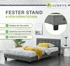 A bedroom scene featuring a grey upholstered bed with patterned bedding and a yellow throw blanket, with marketing text and a close-up detail of the bed frame and legs. Náhled obrázku produktu