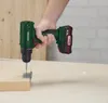 A hand holding a cordless drill, screwing a metal bracket onto a wooden plank. Produktbild-Vorschau