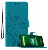 A teal flip case for a Motorola phone is shown open, with the phone inside displaying its screen. A wrist strap is attached to the side of the case. Náhľad obrázku produktu