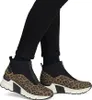 A pair of women's leopard print ankle boots with black accents and white soles, worn with black jeans. Anteprima dell’immagine prodotto
