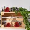 A wooden crate filled with decorative items including roses, glass orbs with lights, and a glass bottle, with greenery draped over the top. Produktbild-Vorschau