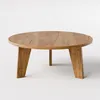 A round wooden coffee table with three angled legs, presented against a plain white background. Voir les images du produit