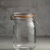 A clear glass jar with a silver wire bail closure and an orange rubber seal, set against a textured gray background. Produktbild-Vorschau