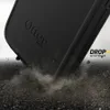 A black Otterbox Defender case for an iPhone is shown falling onto a rough surface, with dust and debris flying. Anteprima dell’immagine prodotto