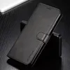 A black leather flip case for a smartphone is shown on a dark wooden surface, with a white object in the background. Produktbild-Vorschau