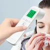 A hand holds a white digital infrared thermometer to a person's forehead, while the person blows their nose with a tissue. Produktbild-Vorschau