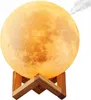 A moon-shaped lamp with a wooden stand, emitting a soft orange glow and a wisp of smoke from the top. Podgląd zdjęcia produktu