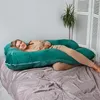 A woman is lying on a bed with a large green pregnancy pillow. Náhled obrázku produktu