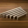 A collection of metal cabinet handles arranged diagonally on a wooden surface. Produktbild-Vorschau