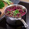 A pot of food is on a stovetop, with ingredients on a cutting board in the background. Voir les images du produit