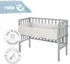 A grey crib with a white quilted bumper pad inside, shown from a slightly elevated side angle. Produktbild-Vorschau