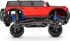 The side view of a red remote-controlled car chassis with its suspension and wheels visible. Podgląd zdjęcia produktu