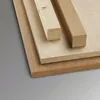 Several pieces of wood, including plywood and lumber, are stacked on a plain gray background. Voir les images du produit