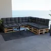A sectional sofa made of wooden pallets with dark grey cushions is placed on a balcony overlooking the ocean. Anteprima dell’immagine prodotto