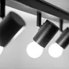A close-up, black and white image of a track lighting fixture with three adjustable spotlights. The spotlights are cylindrical and matte black, with exposed light bulbs. Náhľad obrázku produktu
