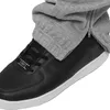 Close-up of a black sneaker with grey sweatpants pulled over it, showing a zipper detail on the sweatpants. Produktbild-Vorschau