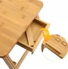 Close-up view of a bamboo laptop table with a drawer extended, showing ventilation slots and a support. Produktbild-Vorschau