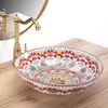 A colorful ceramic basin with a decorative pattern sits on a wooden countertop next to a brass faucet. Náhled obrázku produktu